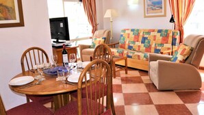 A living room with a round dining table, chairs, a sofa, and a television. - 9A sea views and wifi (Calpe/Calp)