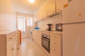 A modern kitchen with white cabinets, a built-in oven, and a microwave.