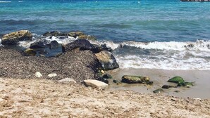 A rocky beach with waves, a distant mountain, and a red lighthouse. - apartment 46A VORA 2 bedroom (Calpe/Calp)