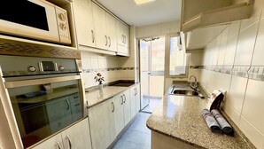 A modern kitchen with white cabinets, a built-in oven, a microwave, and a granite countertop. - apartment 46A VORA 2 bedroom (Calpe/Calp)