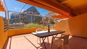 A balcony with a table and chairs, a bottle of champagne, and a view of a mountain and buildings. - 21C VORA 1 bedroom with sea views and wifi (Calpe/Calp)