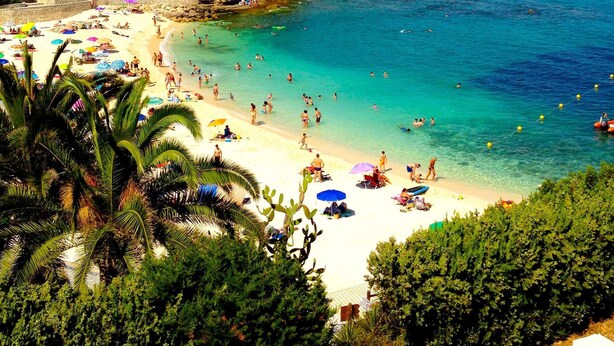 A beach with clear turquoise water, white sand, and numerous umbrellas. - 21C VORA 1 bedroom with sea views and wifi (Calpe/Calp)