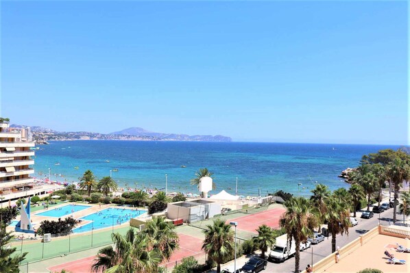 Een hotel aan de kust met een zwembad, palmbomen en uitzicht op zee.