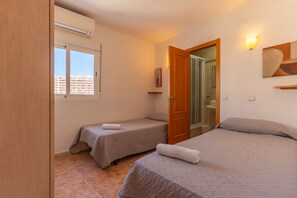 A hotel room with two beds, a shower, and a window with a view of buildings. - 25D Voramar, 2-Bedroom (Calpe/Calp)