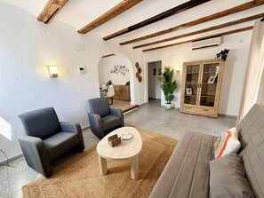 Una sala de estar con un sofá, dos sillones, una mesa de centro y un aparador de madera.