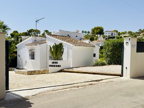 Una entrada con portón, un edificio blanco con la leyenda 'SAN ANDRES' y un cactus al frente.