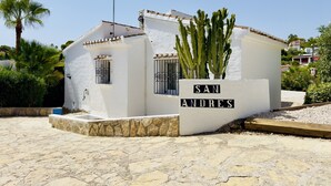 Un pequeño edificio blanco con un letrero que dice 'SAN ANDRES' y un cactus en primer plano.
