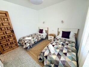 Habitación de hotel con dos camas, una puerta de madera y un pequeño tapete.