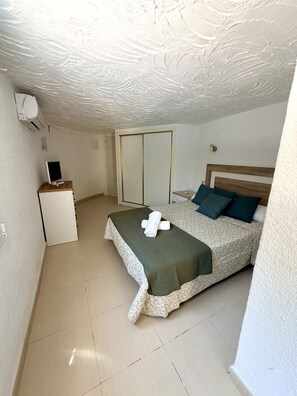 Een slaapkamer met een bed, een bureau en een kledingkast.