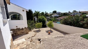 Un quartier résidentiel avec un bâtiment blanc, une allée gravillonnée et un petit arbre.