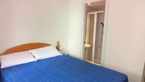Ein Schlafzimmer mit einem Bett, einem Holz-Kopfteil und einer Tür zu einem Badezimmer.