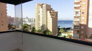 Ein Balkon mit Blick auf hohe Gebäude und das Meer.