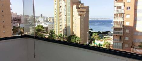 A balcony with a view of tall buildings and the sea.
