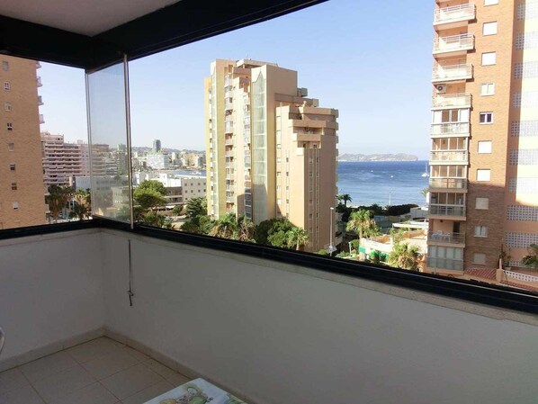 A balcony with a view of tall buildings and the sea.
