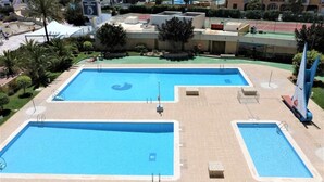 Ein Poolkomplex mit mehreren Becken und einer umlaufenden gepflasterten Fläche.