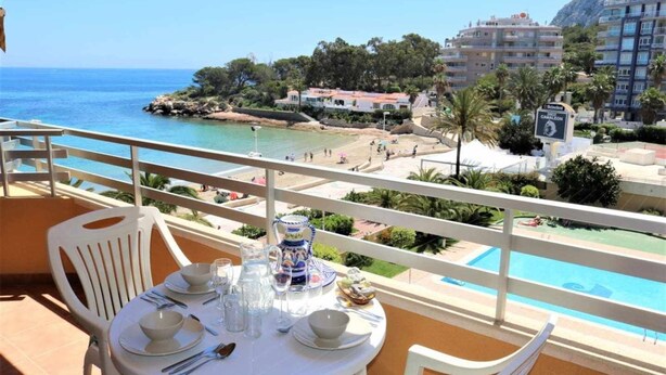 Ein Balkon mit Esstisch, mit Blick auf Pool und Strand.
