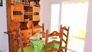 Ein Essbereich mit einem Holztisch und Stühlen, einer Tischdecke mit grünen Punkten und einem Bücherregal voller Bücher und Dekoration.
