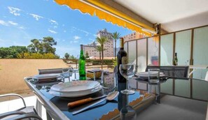 A dining area with a table set for two, a bottle of wine, and a glass. The table is near a window with a view of a building and trees. - 112 Calpeplace with large terrace, wifi and pool (Calpe/Calp)