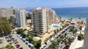 A coastal cityscape with high-rise buildings, a parking lot, and a beach area with a pool. - Apollo17 E39, 2 bedrooms (Calpe/Calp)