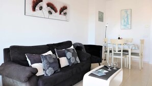 A modern living room with a black sofa, a dining table with chairs, and artwork on the walls. - Apollo17 E39, 2 bedrooms (Calpe/Calp)