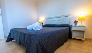 A neatly made bed with a dark quilt, a rolled towel, and a small potted plant on the nightstand. - INMOWEAVER 22B ES With beautiful views of the sea (Calpe/Calp)