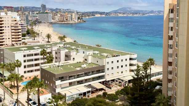 A coastal hotel with multiple floors, a rooftop pool, and a beach view.