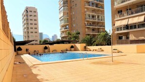 A swimming pool area with a tiled deck, surrounded by high-rise buildings.