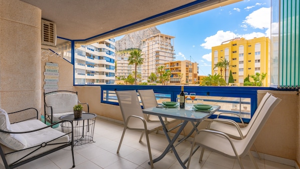 A balcony with a table, chairs, and a bottle of wine.