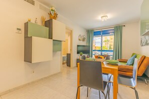 A modern living space with a dining area, a sofa, and a TV.