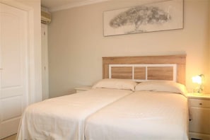 A double bed with a wooden headboard, a bedside table with a lamp, and a painting on the wall.