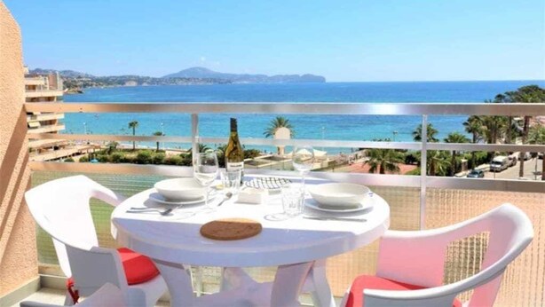 Ein Balkon mit Tisch für zwei Personen, Blick auf Strand und Meer.