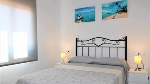 Ein Schlafzimmer mit einem Bett, zwei Nachttischen mit Lampen und zwei an der Wand hängenden Bildern.