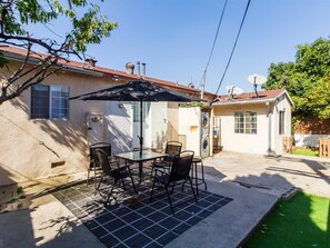 Eine Terrasse mit Tisch und Stühlen, einer Waschmaschine und einem kleinen Gebäude mit Satellitenschüssel.