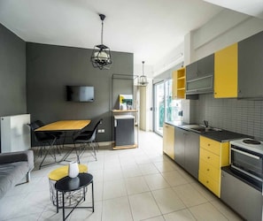 A modern kitchen with a dining area, a flat-screen TV mounted on the wall, and a built-in oven.