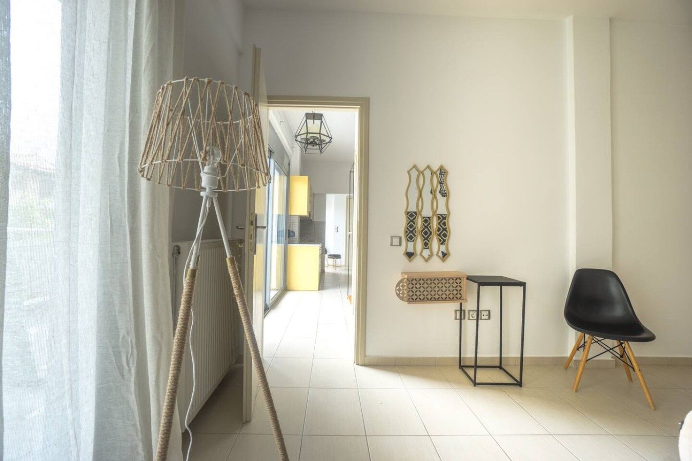 A modern living room with a floor lamp, a black chair, and decorative wall art.