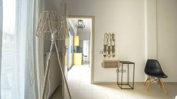A modern living room with a floor lamp, a black chair, and decorative wall art.