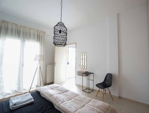 A bedroom with a bed, a chair, a lamp, and a hanging light fixture.