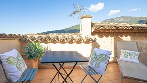 A terrace with a table, two chairs, a potted plant, and a TV antenna. - L'Angel by Rentallorca (Biniaraix)