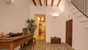 A narrow hallway with a wooden table and chairs, a potted plant, and a small chest of drawers. - L'Angel by Rentallorca (Biniaraix)