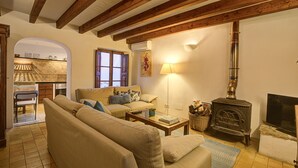 A cozy living room with a sofa, a coffee table, a fireplace, and a television. - L'Angel by Rentallorca (Biniaraix)