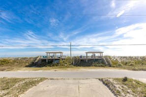 A coastal walkway with two wooden gazebos, a concrete viewing platform, and a clear sky.