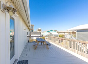 A wooden deck with a picnic table, a railing, and a view of other buildings. - Saltwater Gospel - Classic 2nd Row Home - 4 Bedrooms & Easy Beach Access (Surf City)