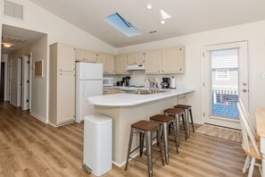 A modern kitchen with a central island, bar stools, and a view to the outside.