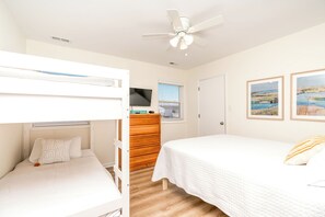 A bedroom with bunk beds, a wooden dresser, a television, and two framed pictures on the wall. - Saltwater Gospel - Classic 2nd Row Home - 4 Bedrooms & Easy Beach Access (Surf City)