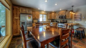 A spacious kitchen with wooden cabinets, a large dining table, and a built-in microwave.