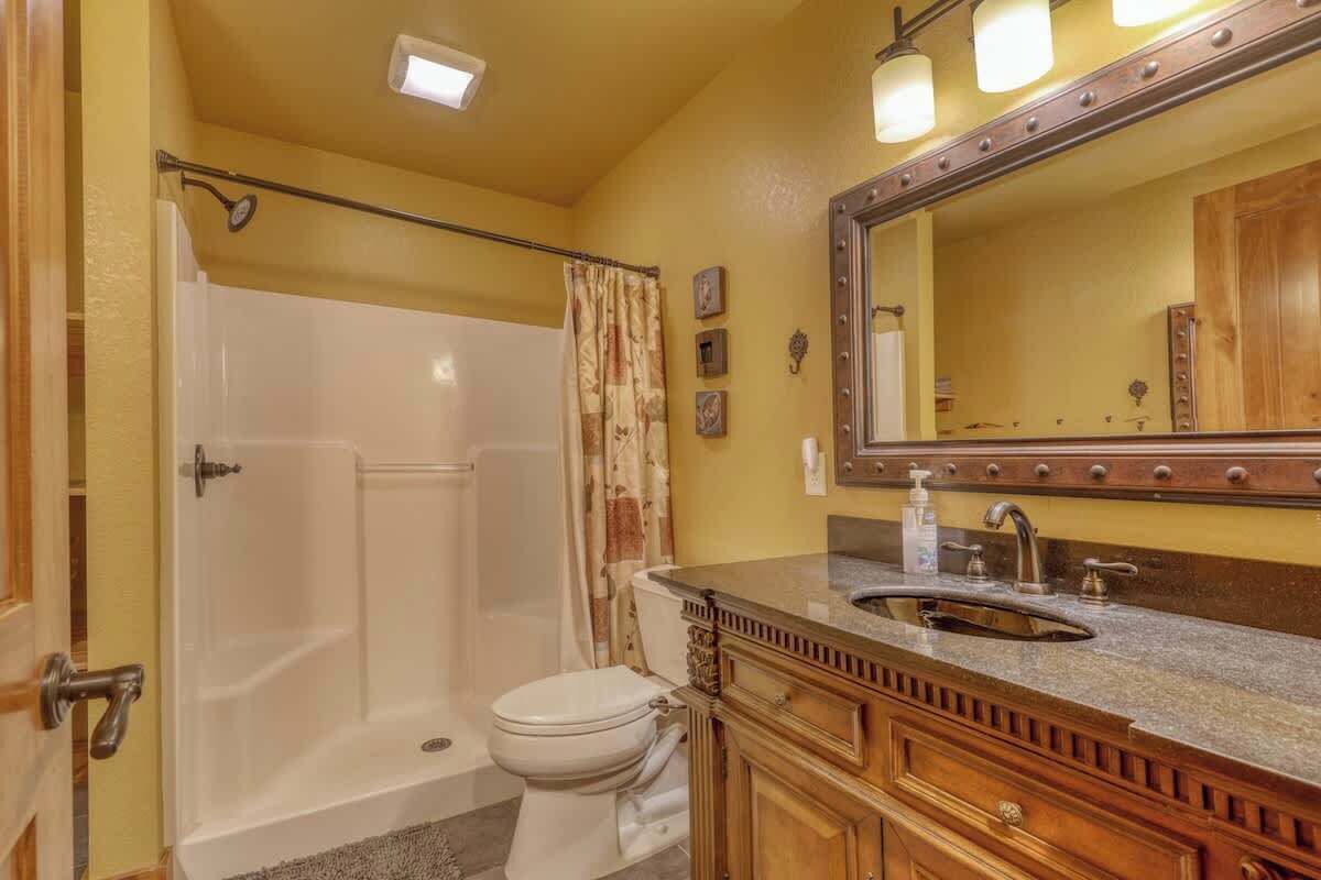 A bathroom with a bathtub, toilet, vanity with a sink, and a large mirror.