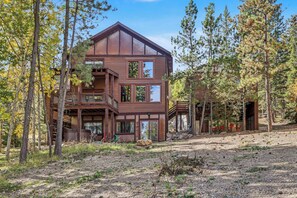 A multi-level wooden cabin with a balcony, surrounded by trees.
