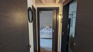 A narrow hallway with wooden flooring leading to a bedroom with a bed and a nightstand. - Le Ch'ti Alsacien ***, duplex apartment for 4/6 people in the heart of Eguisheim (Eguisheim)