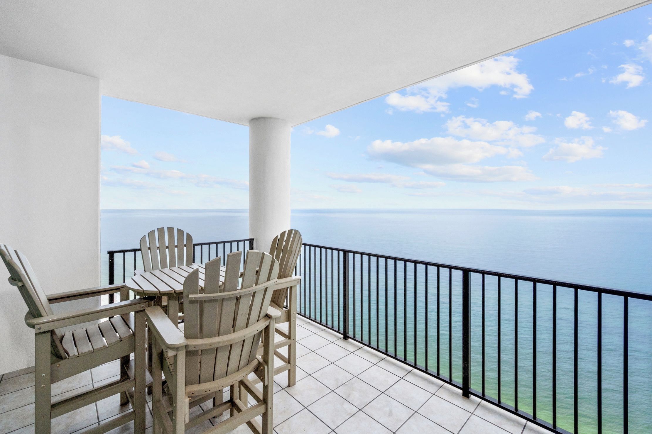 A balcony with a view of the ocean, featuring a table and chairs.