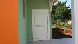A white door with a simple design, set in a building with green and orange walls.